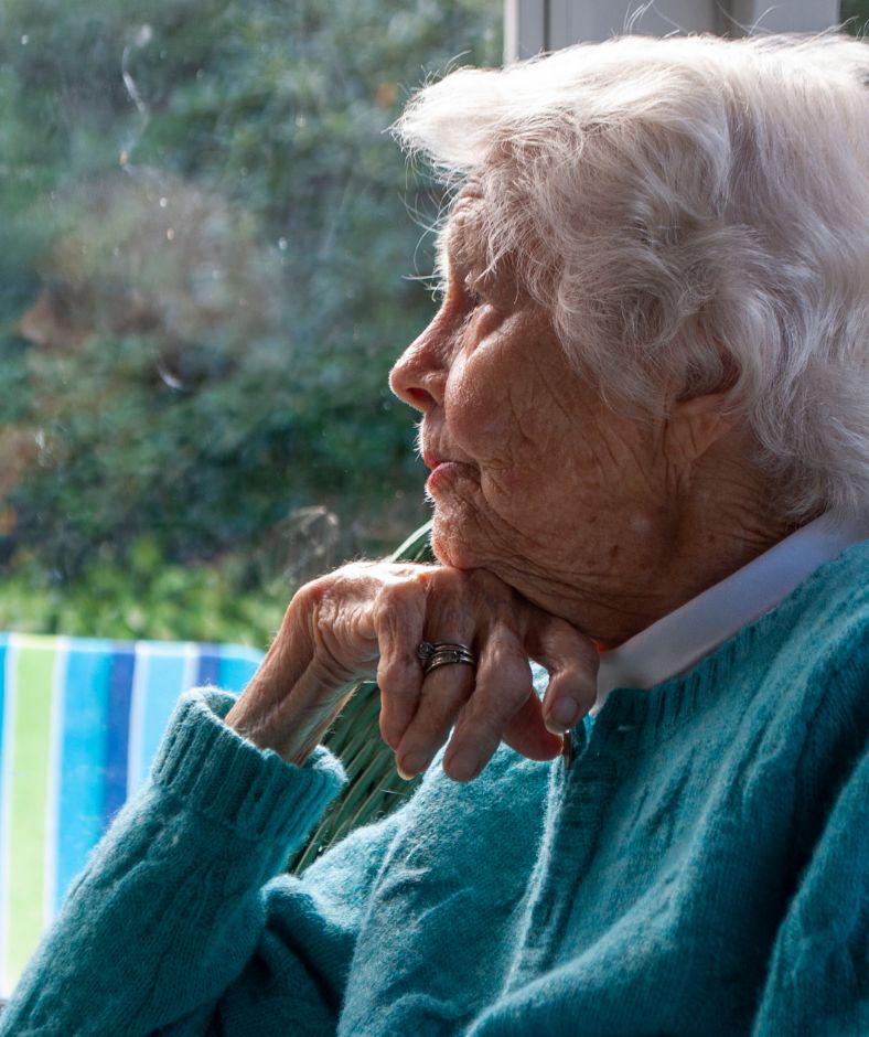 אישה קשישה צופה מבעד לחלון