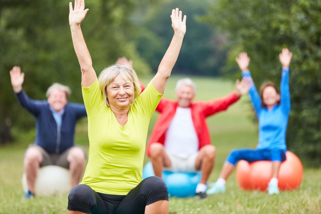 קשישים עושים פילאטיס עם כדור בדשא