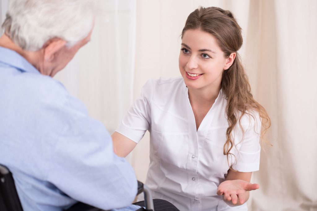 מטפלת שיושבת מול קשיש (רואים את הגב שלו)