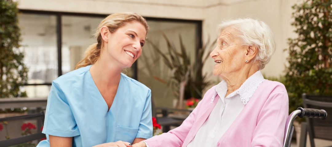 קשישה בכיסא גלגלים ולידה יושבת מטפלת