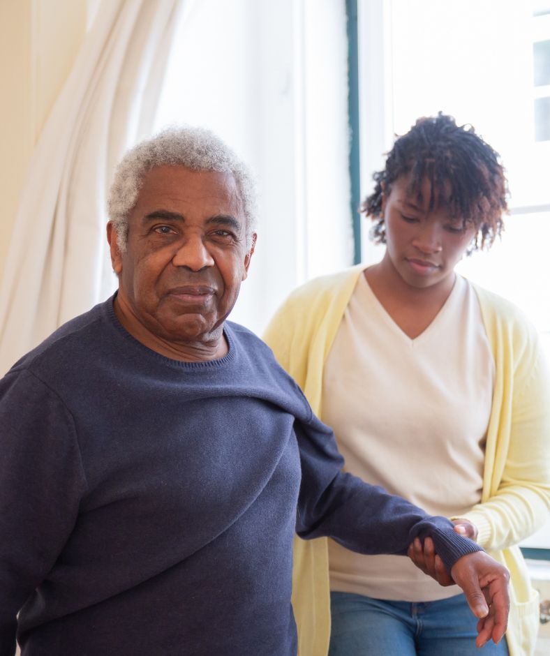 קשיש עומד ומטפלת אוחזת בידו