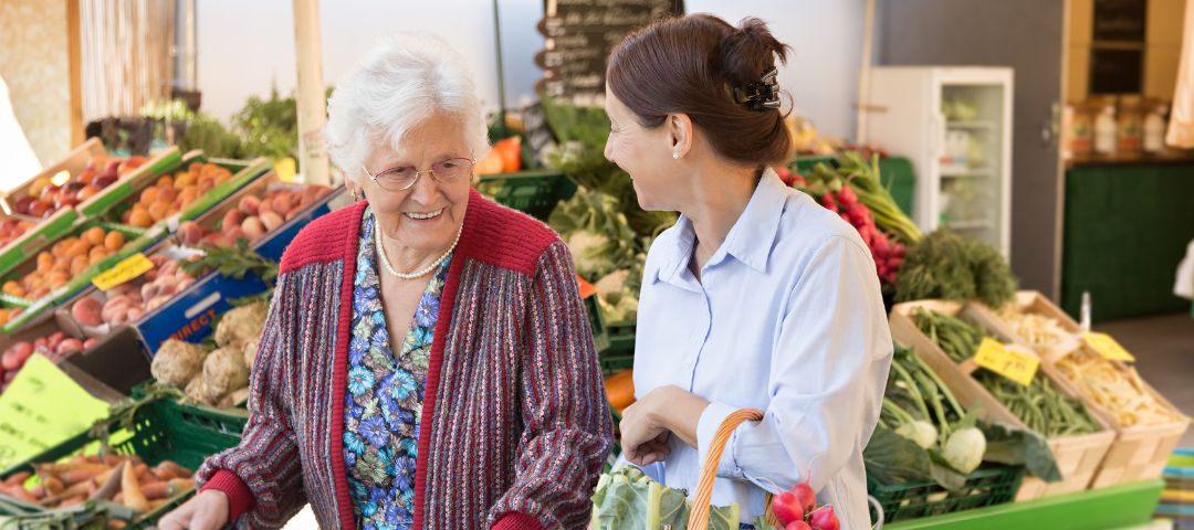 קשישה ואישה באזור הירקות בסופר