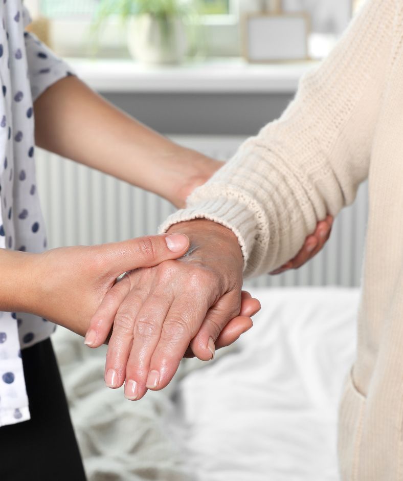מטפלת מחזיקה את היד של הקשישה
