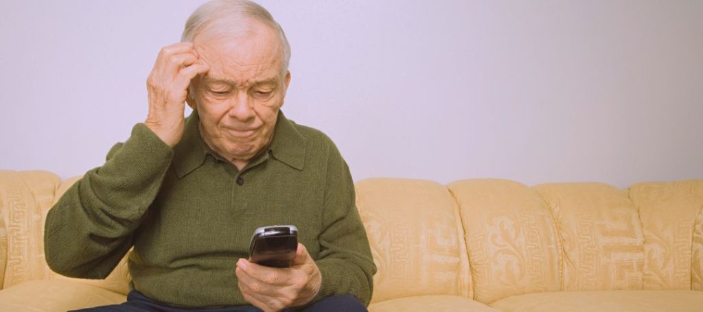 קשיש מבולבל יושב ומסתכל בטלפון שלו