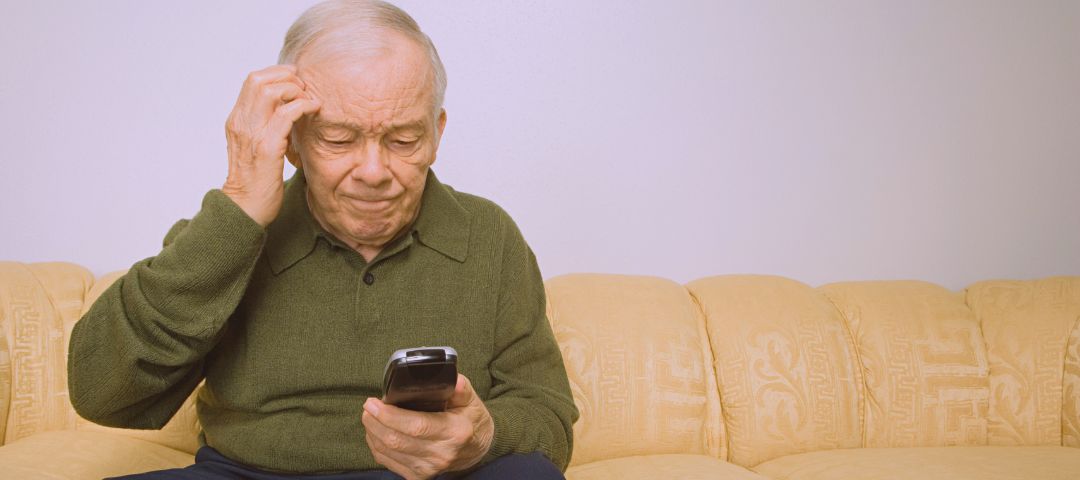 קשיש מבולבל יושב ומסתכל בטלפון שלו