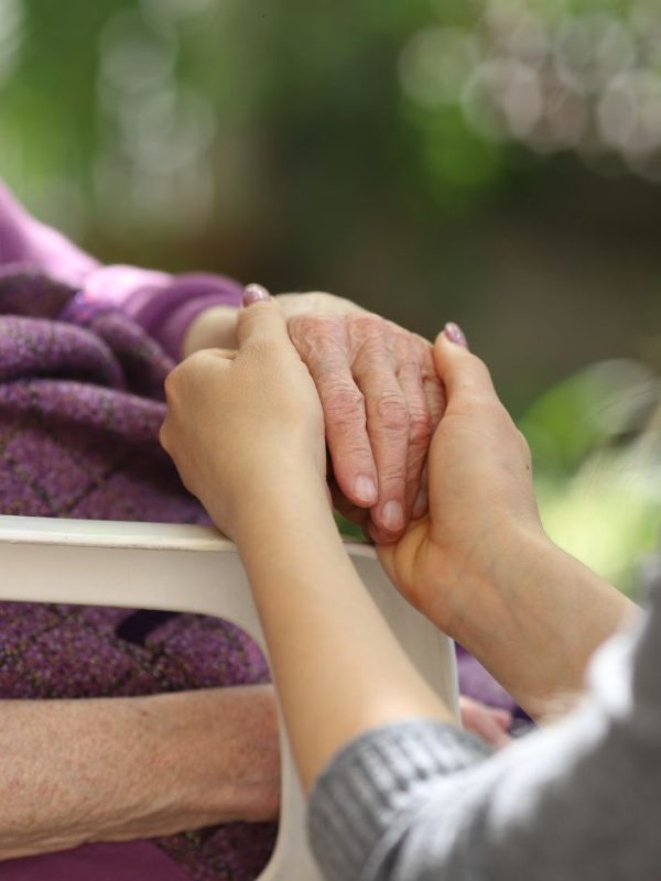 אישה מחזיקה בידיה יד של אישה קשישה