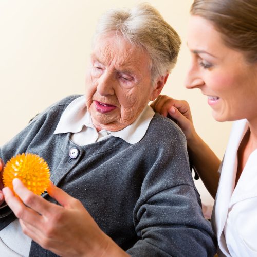 37893866 - nurse giving physical therapy with massage ball to senior woman in wheelchair