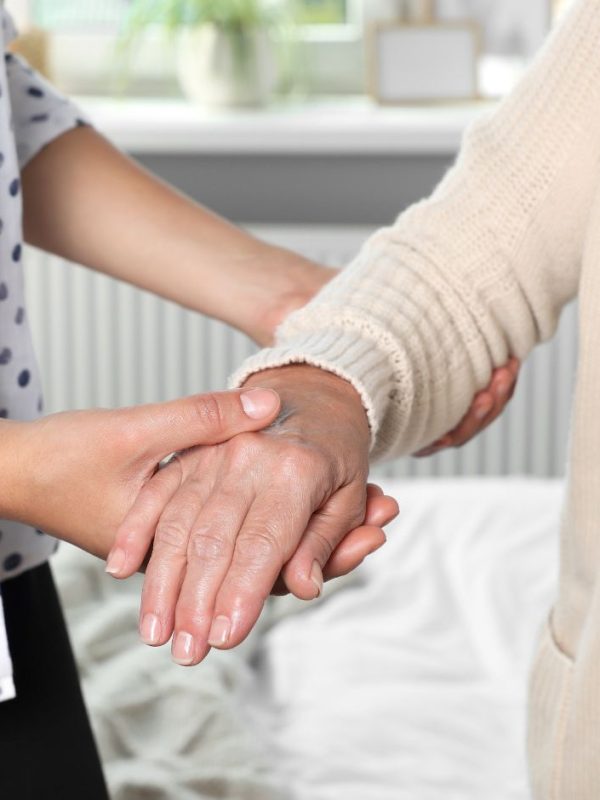 מטפלת מחזיקה את היד של הקשישה