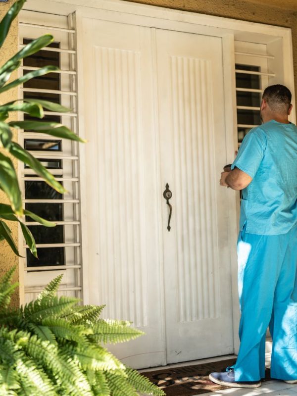 מטפל מקיש בדלת של בית